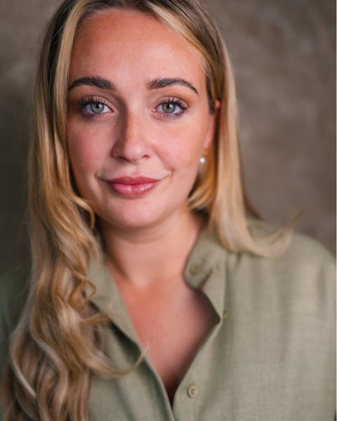 Portrait of a woman with blonde hair wearing a sage green button-up shirt