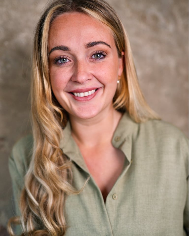 Woman with long blonde wavy hair wearing a dark navy sleeveless top, smiling at the camera